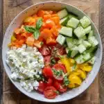 Delicious cottage cheese veggie salad with cucumber, cherry tomatoes, bell peppers, and fresh basil